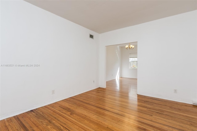 unfurnished room featuring a notable chandelier and light hardwood / wood-style floors