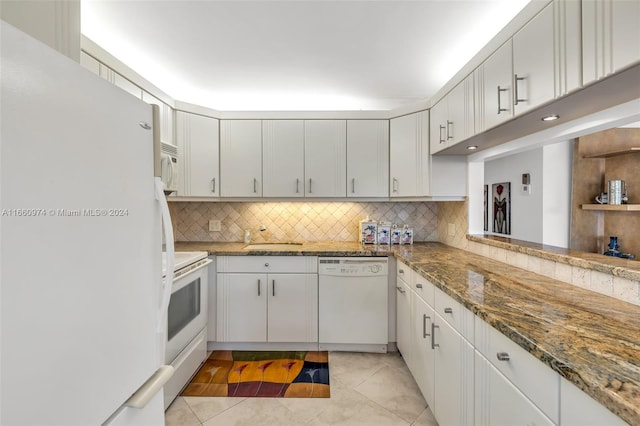 kitchen with light tile patterned flooring, white cabinetry, white appliances, backsplash, and dark stone countertops