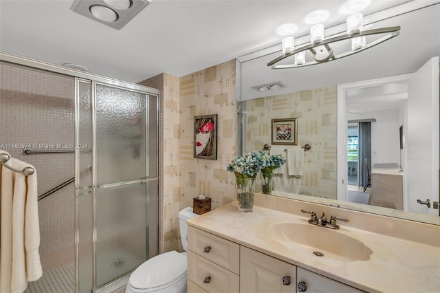 bathroom with vanity, toilet, and a shower with door