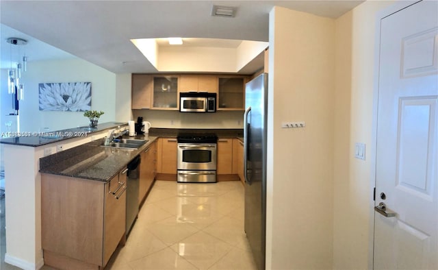 kitchen featuring light tile patterned flooring, sink, kitchen peninsula, stainless steel appliances, and dark stone countertops