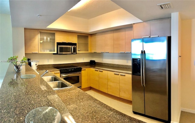 kitchen with light brown cabinets, light tile patterned floors, sink, kitchen peninsula, and stainless steel appliances