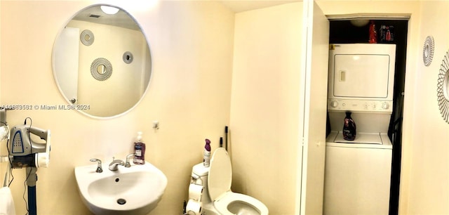 bathroom featuring stacked washer and clothes dryer, toilet, and sink