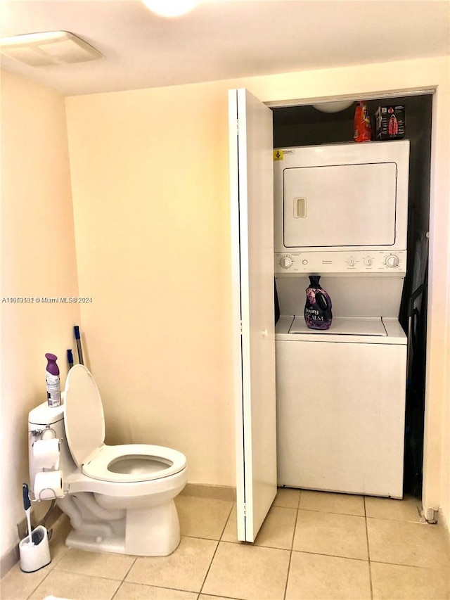 bathroom with toilet, tile patterned flooring, and stacked washing maching and dryer