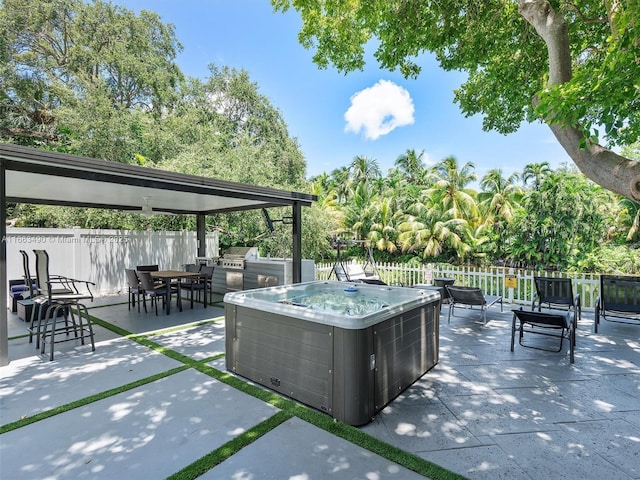 view of patio featuring an outdoor kitchen, fence, a grill, and a hot tub