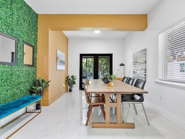 dining room featuring a healthy amount of sunlight, marble finish floor, baseboards, and french doors