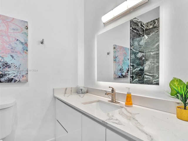 bathroom with a tile shower, vanity, and toilet