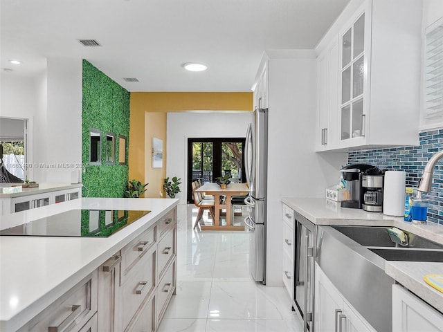 kitchen featuring black electric cooktop, glass insert cabinets, white cabinets, and light countertops