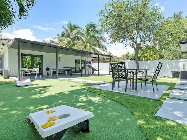 view of community with a lawn, a patio area, and fence