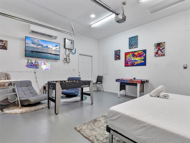 bedroom featuring a textured ceiling, an AC wall unit, concrete flooring, and electric panel