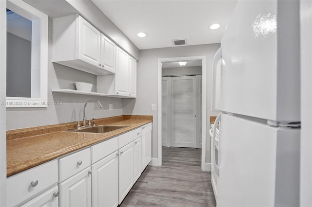 kitchen with white cabinets, sink, white appliances, and light hardwood / wood-style floors