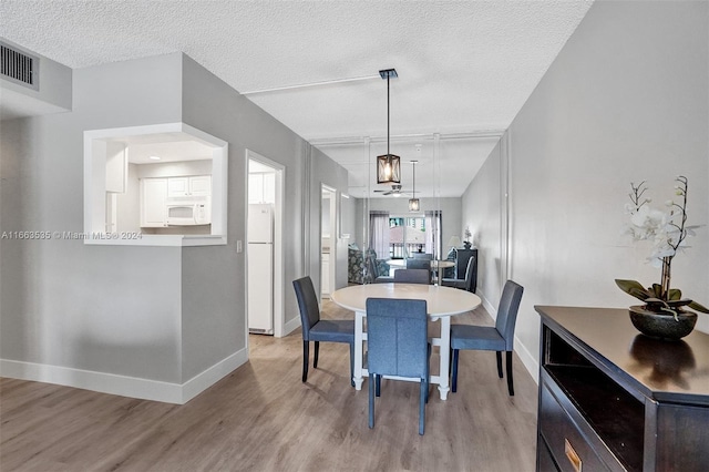 dining room featuring a textured ceiling and light hardwood / wood-style flooring