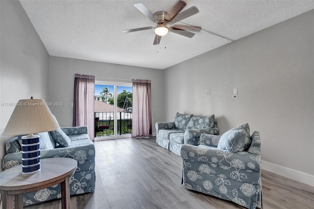 living room featuring ceiling fan, wood-type flooring, and a textured ceiling