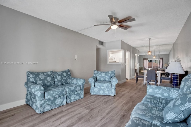 living room with a textured ceiling, ceiling fan, and hardwood / wood-style floors