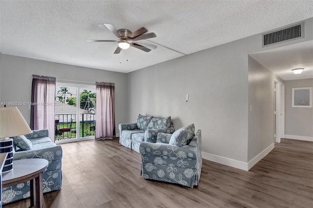 living room featuring ceiling fan, wood-type flooring, and a textured ceiling