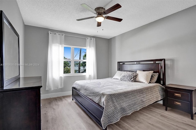 bedroom featuring ceiling fan, a textured ceiling, and light hardwood / wood-style flooring