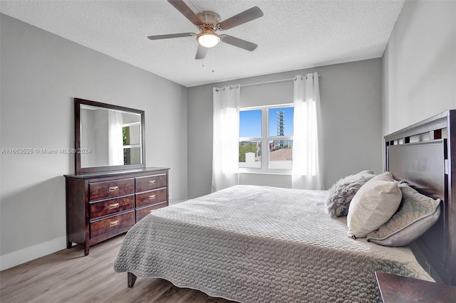 bedroom with ceiling fan, a textured ceiling, and light hardwood / wood-style floors