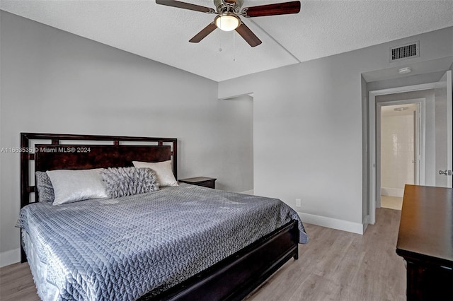 bedroom with ceiling fan, a textured ceiling, and light hardwood / wood-style flooring