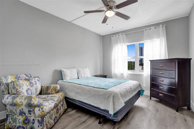 bedroom featuring ceiling fan, light wood-type flooring, and a textured ceiling