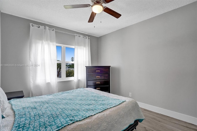 bedroom featuring a textured ceiling, ceiling fan, and light hardwood / wood-style floors