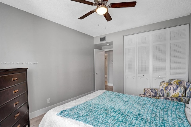 bedroom featuring light wood-type flooring, a closet, a textured ceiling, and ceiling fan