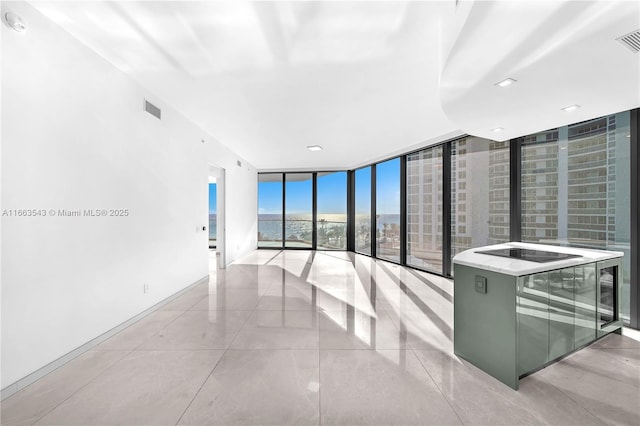 empty room featuring light tile patterned flooring and a wall of windows