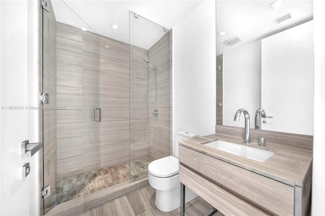 bathroom with vanity, a shower with shower door, and toilet