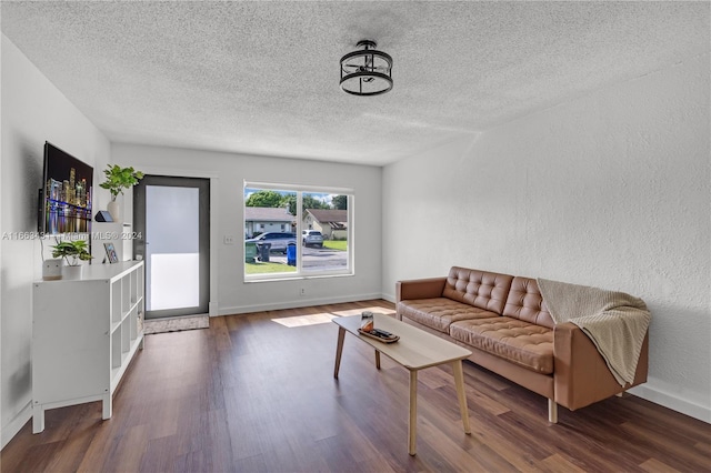 living room with a textured ceiling and dark hardwood / wood-style flooring