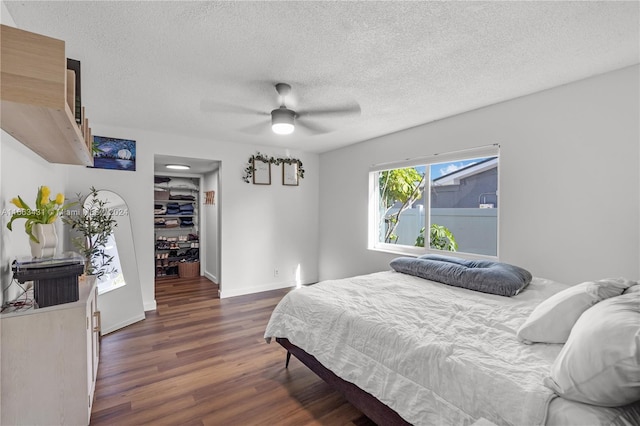 bedroom featuring ceiling fan, a textured ceiling, a closet, dark hardwood / wood-style floors, and a spacious closet