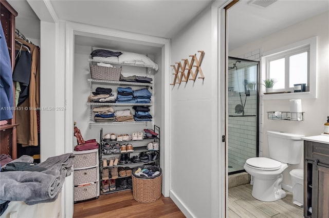 bathroom featuring walk in shower, vanity, toilet, and wood-type flooring