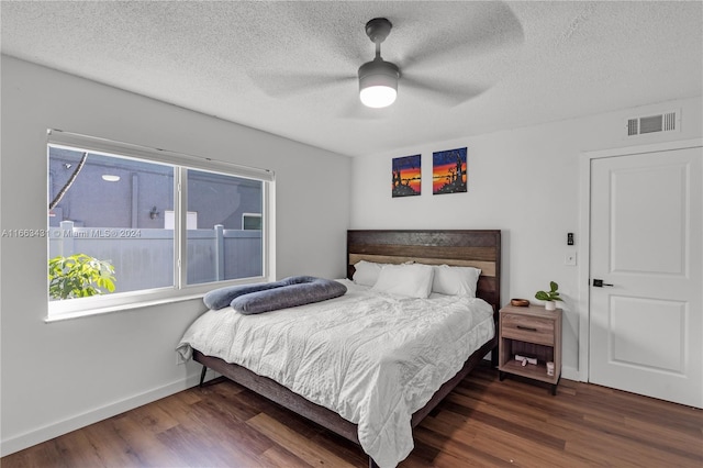 bedroom featuring ceiling fan, dark wood-type flooring, and a textured ceiling