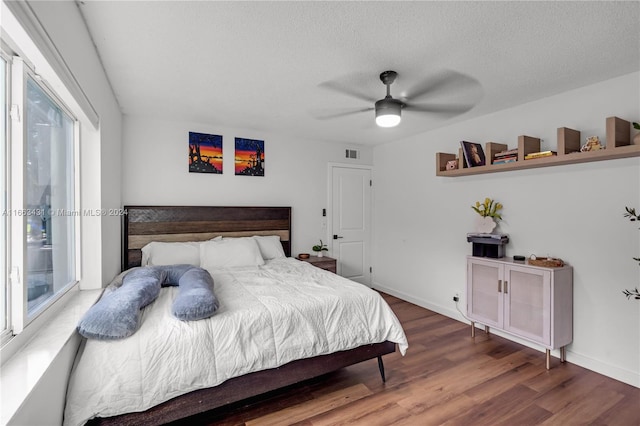 bedroom featuring wood-type flooring, ceiling fan, and a textured ceiling