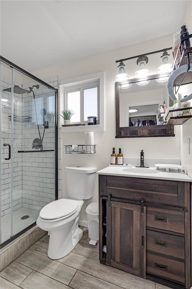 bathroom featuring vanity, a shower with shower door, toilet, and hardwood / wood-style flooring