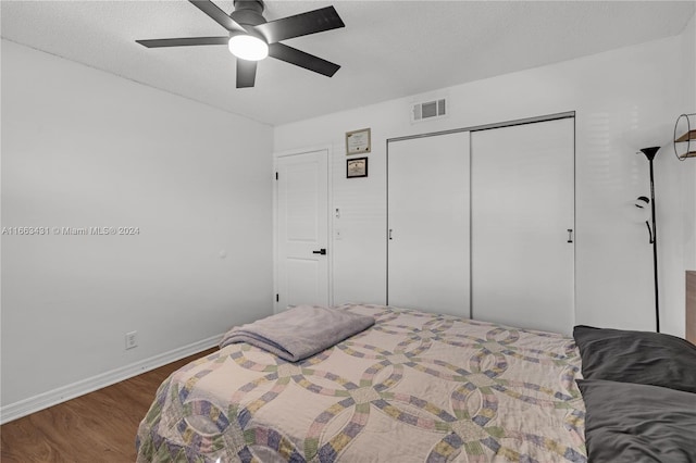 bedroom with a textured ceiling, wood-type flooring, ceiling fan, and a closet