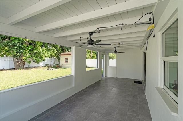 unfurnished sunroom with ceiling fan and beamed ceiling