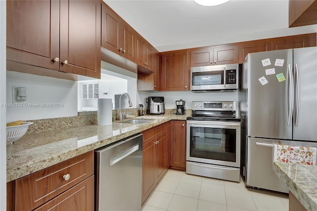 kitchen with light tile patterned flooring, light stone countertops, sink, and stainless steel appliances