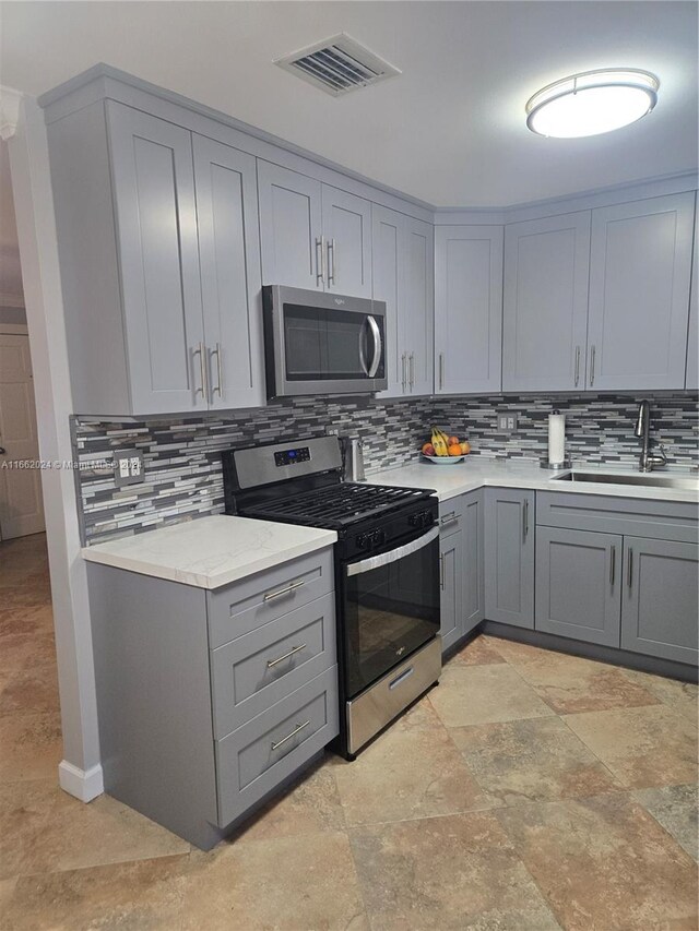 kitchen with gray cabinets, sink, and stainless steel appliances