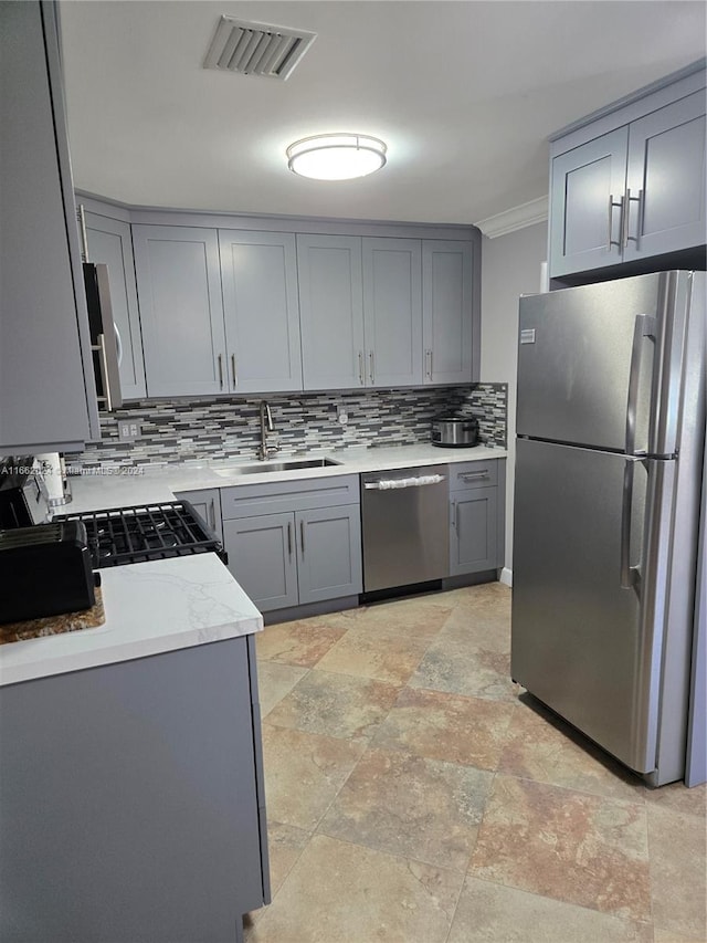 kitchen featuring tasteful backsplash, appliances with stainless steel finishes, sink, gray cabinets, and crown molding