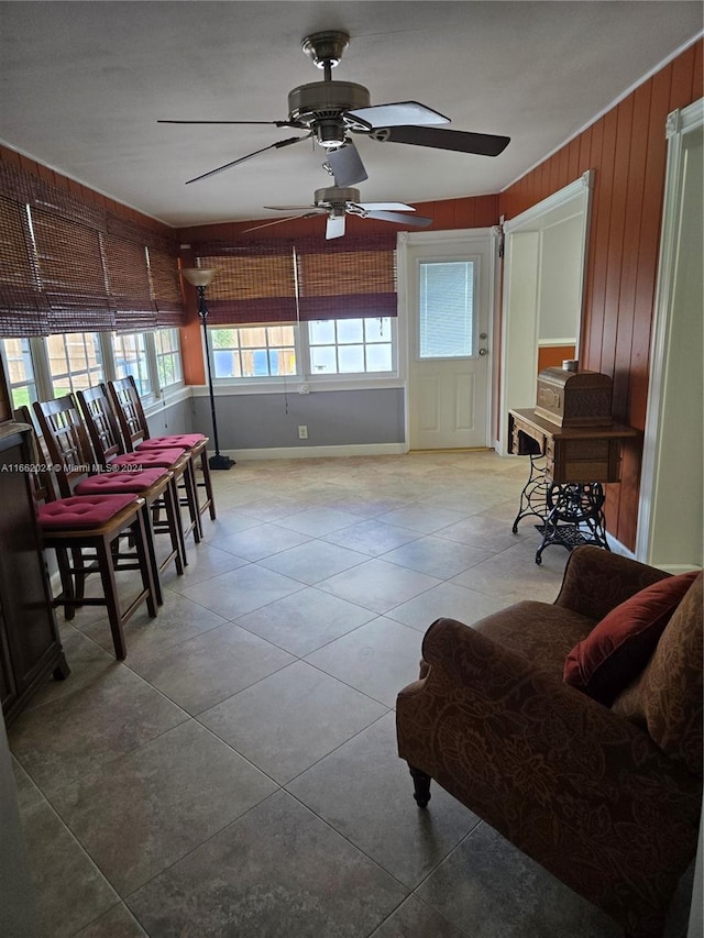 interior space featuring ceiling fan and wood walls