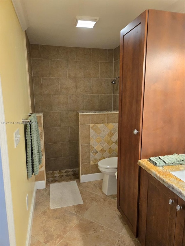 bathroom featuring vanity, a tile shower, tile patterned flooring, and toilet