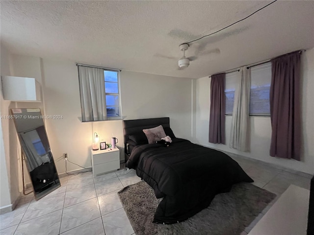 tiled bedroom with ceiling fan, a textured ceiling, and track lighting