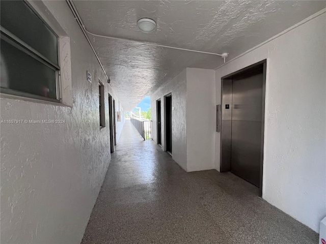 hall featuring a textured ceiling and elevator