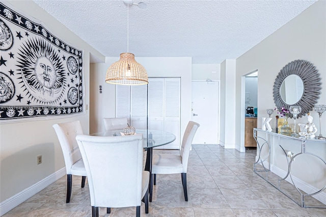 dining space with a textured ceiling and light tile patterned flooring