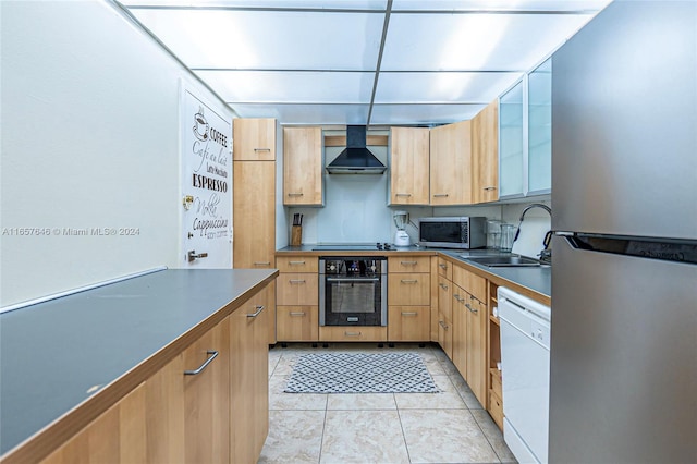 kitchen featuring light tile patterned floors, appliances with stainless steel finishes, wall chimney range hood, and sink