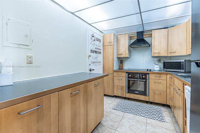 kitchen featuring light tile patterned flooring, cooktop, wall chimney exhaust hood, a drop ceiling, and oven