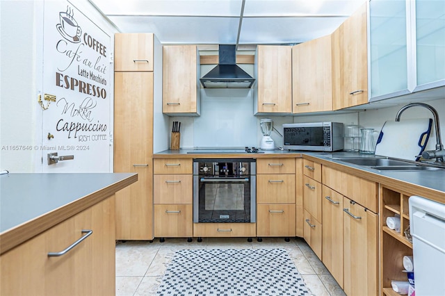 kitchen featuring appliances with stainless steel finishes, light tile patterned floors, light brown cabinetry, sink, and wall chimney range hood