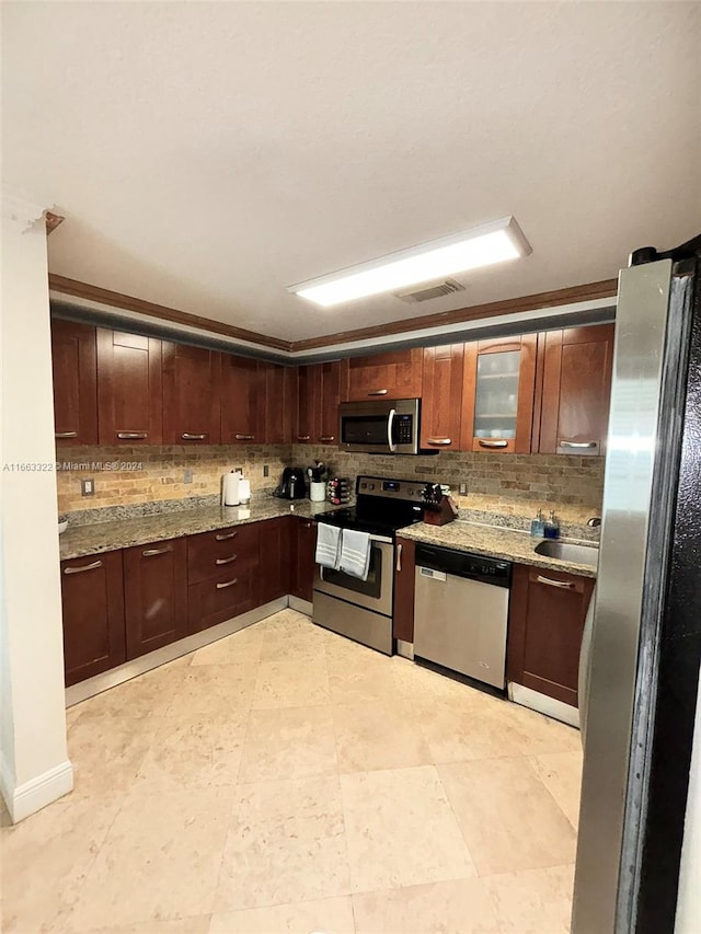 kitchen featuring backsplash, appliances with stainless steel finishes, sink, and light stone countertops