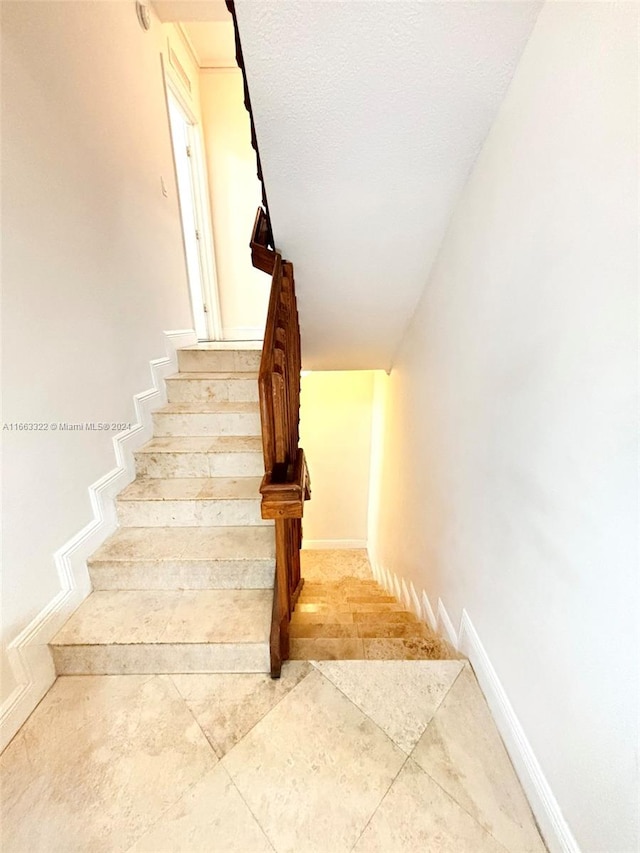 staircase with a textured ceiling and tile patterned flooring