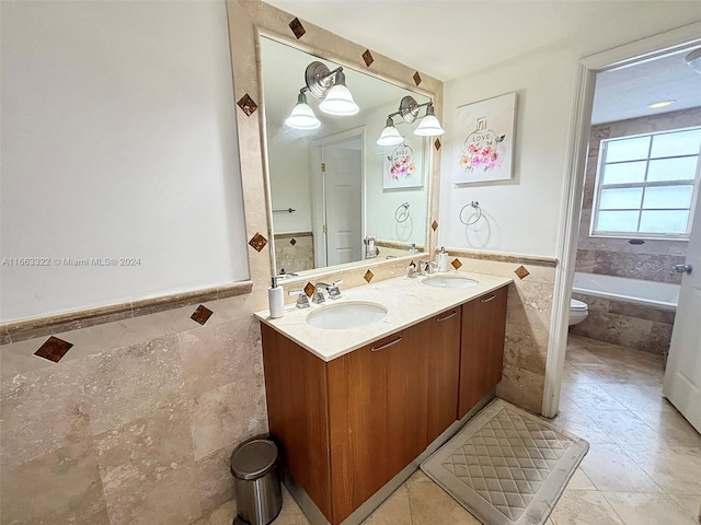 bathroom with tile patterned flooring, vanity, a bath, toilet, and tile walls