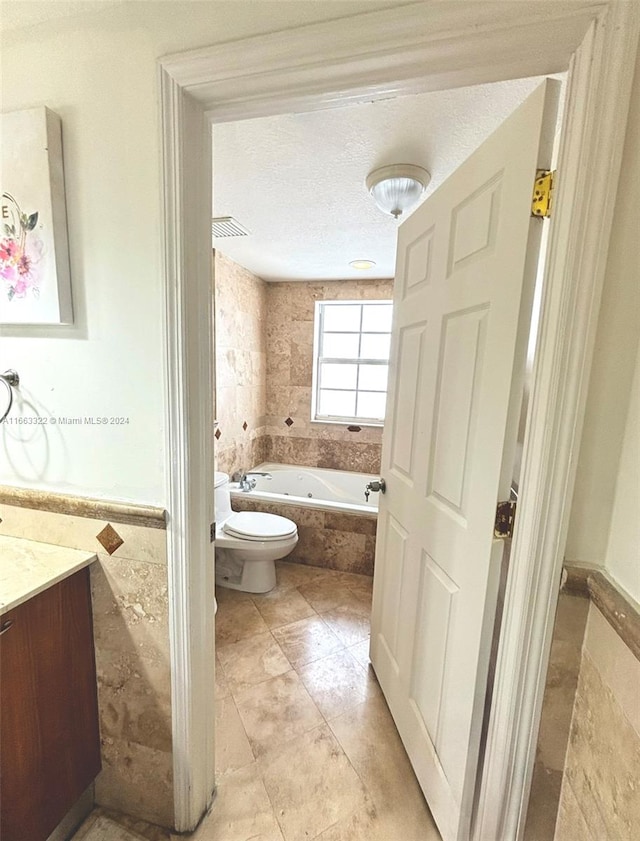 bathroom featuring toilet, a washtub, vanity, and a textured ceiling