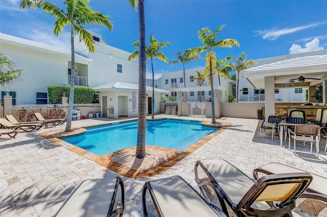 view of pool featuring ceiling fan, an outdoor bar, and a patio